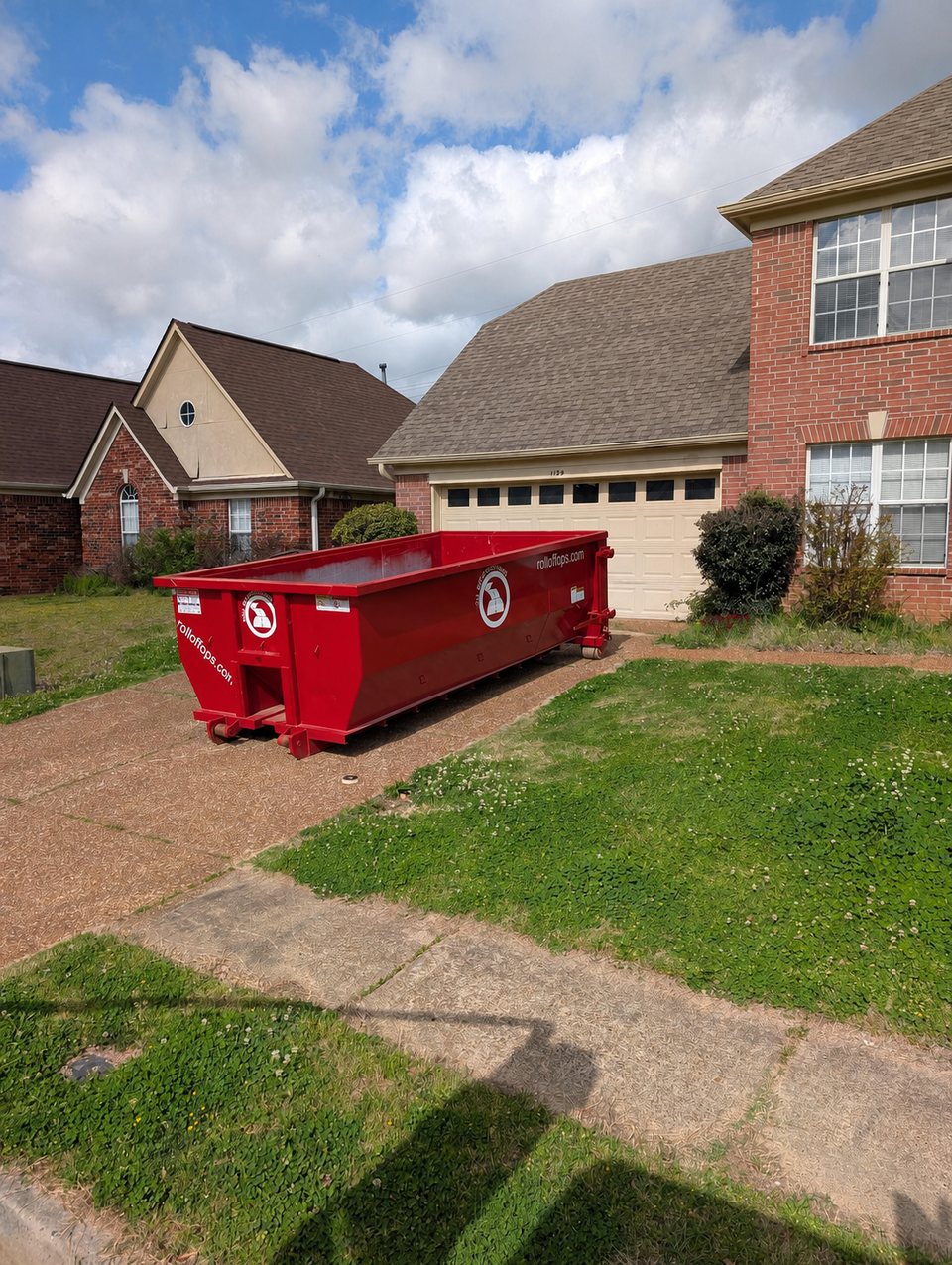 Red 15-yard Roll Off Operations dumpster positioned on a residential driveway