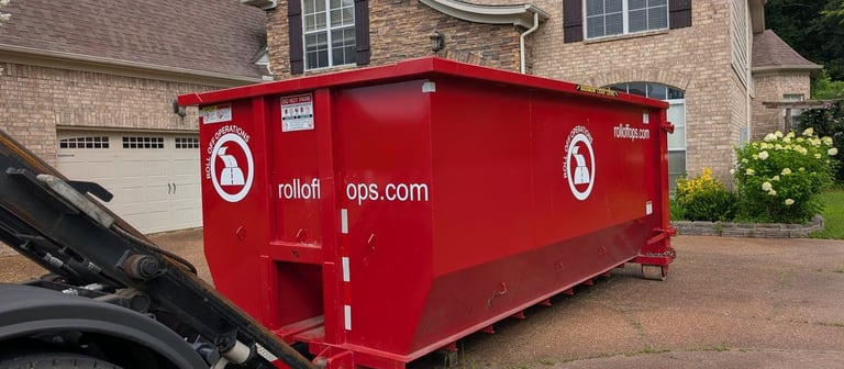Roll Off Operations truck placing a red 20-yard dumpster on a residential driveway